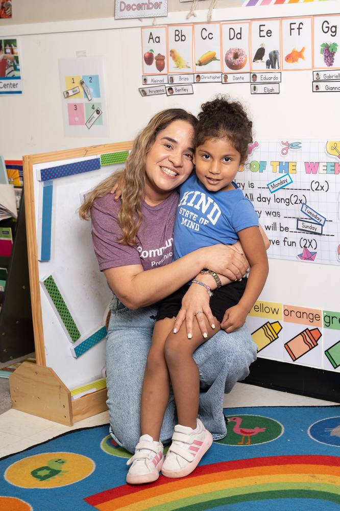 A Community Preschools teacher embracing a student in the classroom